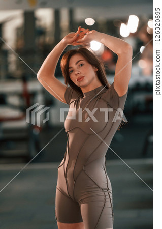 With hands up. Standing and posing. Beautiful woman with sport body type is in the gym With hands up. Standing and posing. Beautiful woman with sport body type is in the gym 126320895