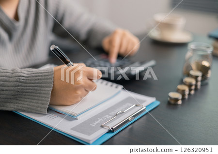 Finance bank tax expense accounting budget money businessman hand use calculator Financial calculate accountant close up calculator with graph chart write office desk Business expense analysis saving 126320951
