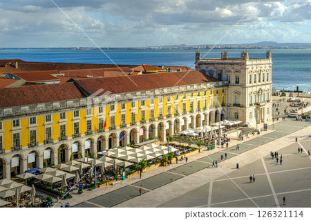Scenic view of Commerce Square or Praca do Comercio in Lisbon, Portugal, iconic yellow Pombaline architecture, bustling outdoor cafes, Tagus River, city life, historic downtown, sunny day, sky with 126321114