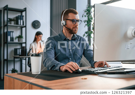 Man is using computer. Two employees are working together in the modern office Man is using computer. Two employees are working together in the modern office 126321397