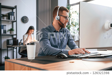 Man is using computer. Two employees are working together in the modern office Man is using computer. Two employees are working together in the modern office 126321398