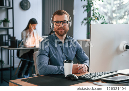 Woman is behind the man. Two employees are working together in the modern office Woman is behind the man. Two employees are working together in the modern office 126321404