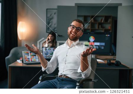 Positive man is smiling. Two employees are working together in the modern office Positive man is smiling. Two employees are working together in the modern office 126321451