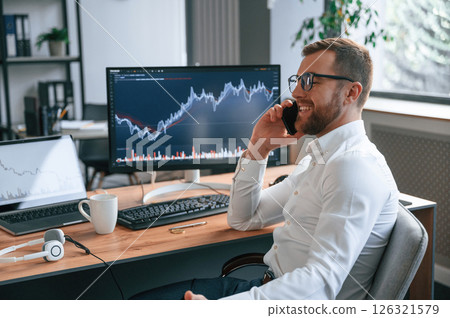 Stock exchange graphs on the screen. Man in formal clothes is working in the modern office. Using computer 126321579