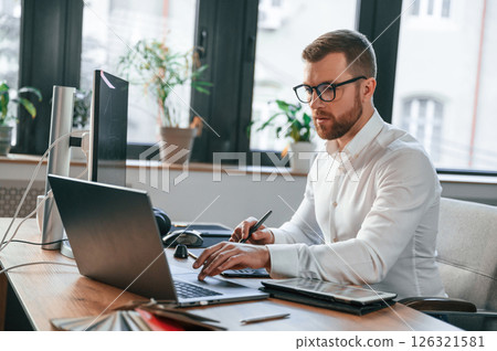 Side view. Man in formal clothes is working in the modern office. Using computer 126321581