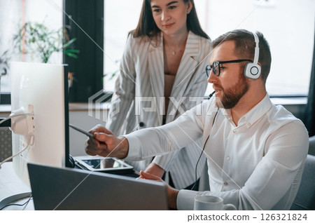 Analyzing information that is on the screen. Two employees are working together in the modern office Analyzing information that is on the screen. Two employees are working together in the modern office 126321824