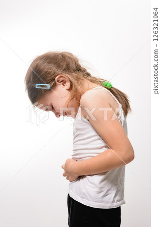 Young girl holding her stomach, appearing unwell. Studio shot against a white background. 126321964