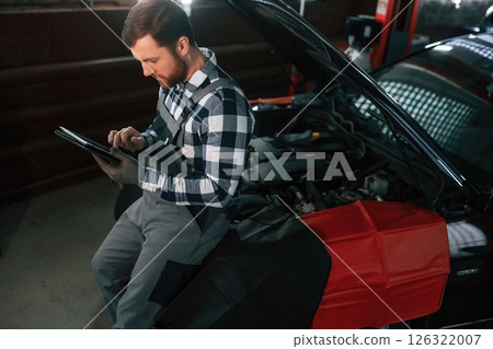 With tablet in hands. Man in uniform is working in the auto salon With tablet in hands. Man in uniform is working in the auto salon 126322007
