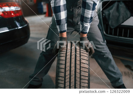 Close up view. Standing with the wheel. Man in uniform is working in the auto salon Close up view. Standing with the wheel. Man in uniform is working in the auto salon 126322009