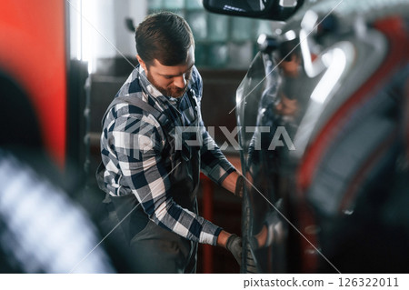 Changing the tire of the car. Man in uniform is working in the auto salon Changing the tire of the car. Man in uniform is working in the auto salon 126322011