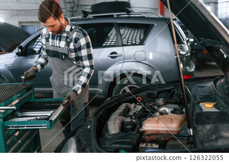 Choosing the tools. Man in uniform is working in the auto salon 126322055