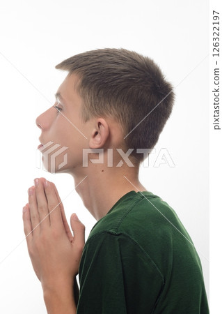 A teenage boy in a green T-shirt folded his hands in prayer. A teenage boy in a green T-shirt folded his hands in prayer. 126322197