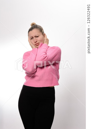 Woman experiencing discomfort, holding her head with hands, eyes closed, pained expression. 126322491