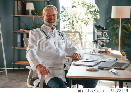 Senior doctor in white coat is at work indoors Senior doctor in white coat is at work indoors 126322559