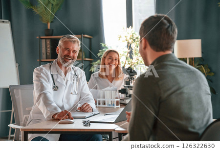 Sitting and talking. Two doctors consult a patient in a clinic 126322630