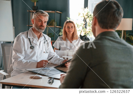 Sitting and talking. Two doctors consult a patient in a clinic Sitting and talking. Two doctors consult a patient in a clinic 126322637