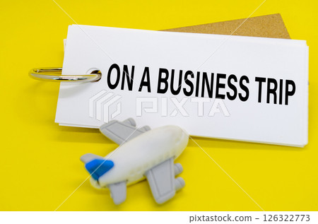 On A Business Trip text on white notepad with small airplane on yellow cover background. Away from office concept On A Business Trip text on white notepad with small airplane on yellow cover background. Away from office concept 126322773