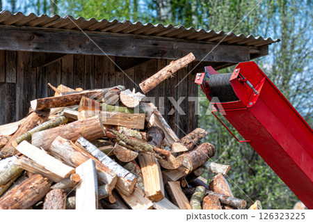 Pile of chopped firewoodin front of a wood chipper 126323225