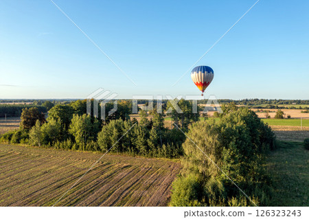 Hot air balloon flying over the field in the evening. Beautiful summer landscape. Hot air balloon flying over the field in the evening. Beautiful summer landscape. 126323243