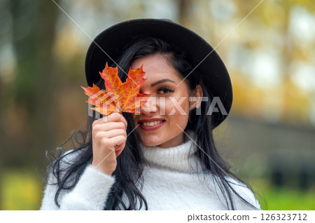 Portrait of a beautiful young woman in the autumn park with maple leaf Portrait of a beautiful young woman in the autumn park with maple leaf 126323712