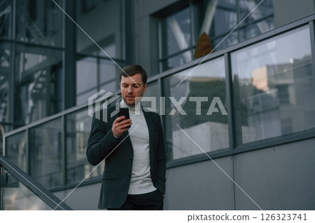 Windows behind the handsome man that is in the formal clothes using smartphone 126323741