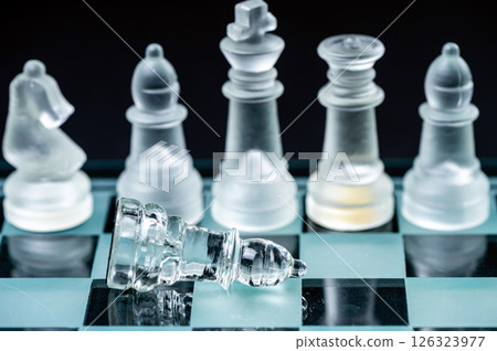 glass, transparent chess pieces on a checkerboard, selective focus, close-up, isolated on black 126323977