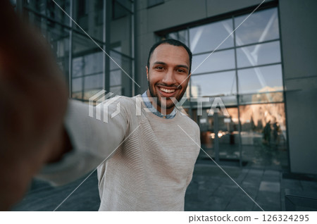 Taking selfie. Handsome black man is outdoors near the business building 126324295