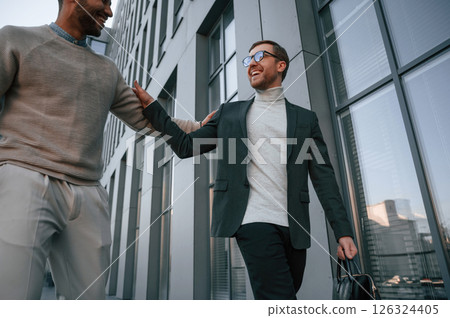 Conception of collaboration. Businessman in formal clothes is with black man outdoors in the city 126324405