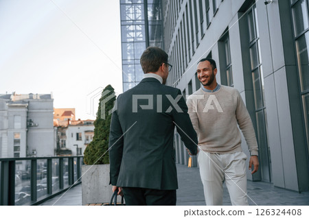 Conception of collaboration. Businessman in formal clothes is with black man outdoors in the city 126324408