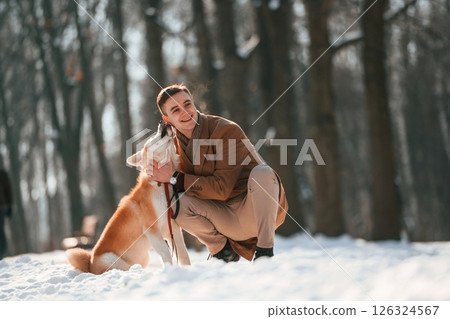 Sitting and embracing the dog. Man having a walk with his akita inu dog outdoors in the park at winter 126324567