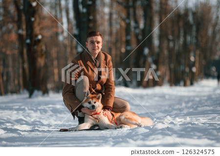 Man having a walk with his akita inu dog outdoors in the park at winter Man having a walk with his akita inu dog outdoors in the park at winter 126324575
