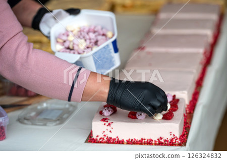 Person decorating cakes with raspberries. Shallow depth of feld Person decorating cakes with raspberries. Shallow depth of feld 126324832