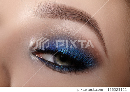 Elegance close-up of female eye with bright dark blue smoky make-up. Macro shot of woman face part. Beauty, cosmetics and makeup. 126325121