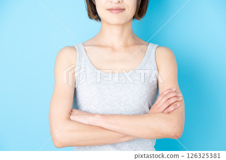 Middle-aged woman in a tank top smiling with her arms folded 126325381