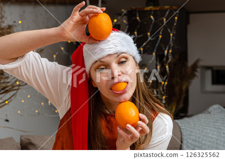 Woman Wearing Santa Hat Balancing Oranges While Celebrating Holiday Festivities Indoors 126325562
