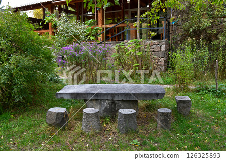 Rustic Stone Table Surrounded by Greenery at a Peaceful Outdoor Location in Autumn Rustic Stone Table Surrounded by Greenery at a Peaceful Outdoor Location in Autumn 126325893
