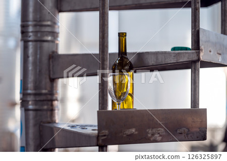A Yellow Bottle and Glass Resting on Metal Shelf in Industrial Winery Setting A Yellow Bottle and Glass Resting on Metal Shelf in Industrial Winery Setting 126325897