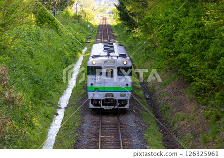 一輛身穿日本國鐵顏色的Kiha列車在翠綠的樹林中穿梭 一輛身穿日本國鐵顏色的Kiha列車在翠綠的樹林中穿梭 126325961