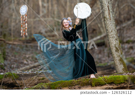 Woman playing a drum in a forest. Shallow depth of feld 126326112