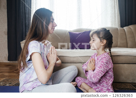 Mom and daughter doing yoga and meditation at home. Home workout together. Fun and active family time 126326363