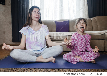 Mom and daughter doing yoga and meditation at home. Home workout together. Fun and active family time Mom and daughter doing yoga and meditation at home. Home workout together. Fun and active family time 126326386