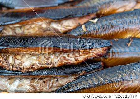 Smoked fish glimmers in the sunlight at a bustling market during midday in a coastal town 126326487