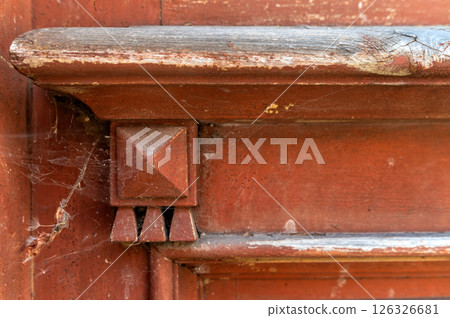 A close-up view of an old wooden doorframe with decorative corner detail and cobwebs A close-up view of an old wooden doorframe with decorative corner detail and cobwebs 126326681