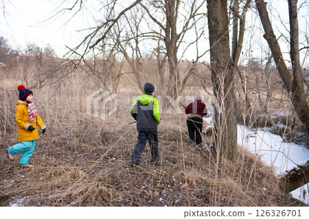 Children exploring a winter landscape by the creek, delighting in nature's beauty while searching for adventure and fun in the chilly afternoon light Children exploring a winter landscape by the creek, delighting in nature's beauty while searching for adventure and fun in the chilly afternoon light 126326701