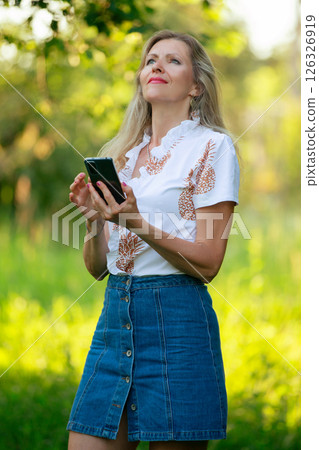 Vertical portrait of a beautiful middle-aged blonde woman with a mobile phone. Vertical portrait of a beautiful middle-aged blonde woman with a mobile phone. 126326919