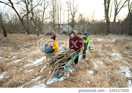 Collecting firewood in winter as children help adults prepare for a cozy evening by the fireplace near a serene forest landscape 126327000