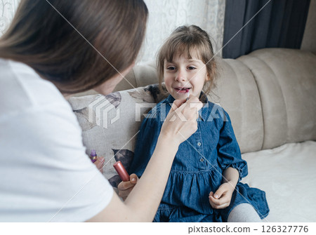 Mother putting makeup on her daughter face and they fool around together. Communication between women in the family. Fun time. Happy family concept. little girl doing her makeup Mother putting makeup on her daughter face and they fool around together. Communication between women in the family. Fun time. Happy family concept. little girl doing her makeup 126327776