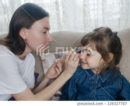 Mother putting makeup on her daughter face and they fool around together. Communication between women in the family. Fun time. Happy family concept. little girl doing her makeup Mother putting makeup on her daughter face and they fool around together. Communication between women in the family. Fun time. Happy family concept. little girl doing her makeup 126327787