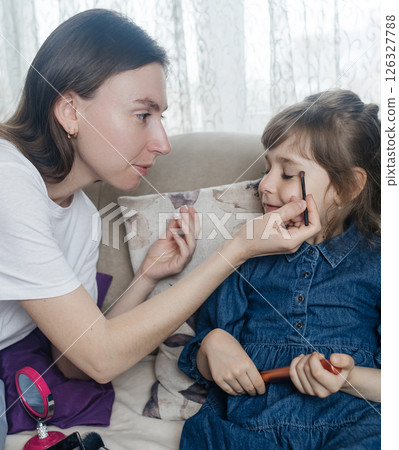Mother putting makeup on her daughter face and they fool around together. Communication between women in the family. Fun time. Happy family concept. little girl doing her makeup Mother putting makeup on her daughter face and they fool around together. Communication between women in the family. Fun time. Happy family concept. little girl doing her makeup 126327788