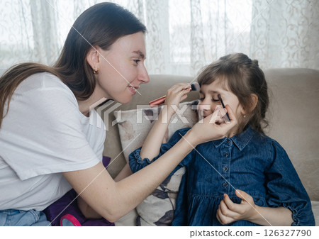 Mother putting makeup on her daughter face and they fool around together. Communication between women in the family. Fun time. Happy family concept. little girl doing her makeup Mother putting makeup on her daughter face and they fool around together. Communication between women in the family. Fun time. Happy family concept. little girl doing her makeup 126327790